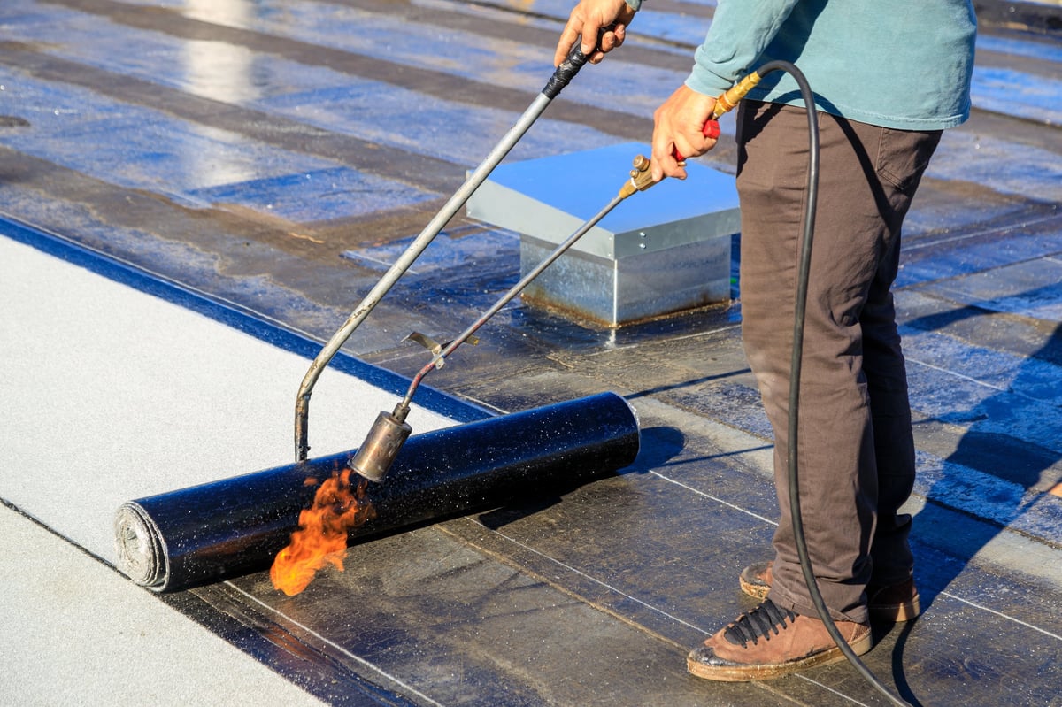 Modified bitumen roofing — torch-down membrane being applied on a flat roof